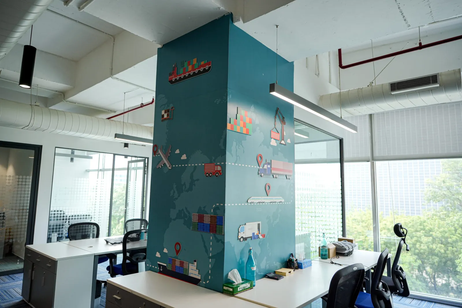 Workspace with a teal world-map pillar (photograph)